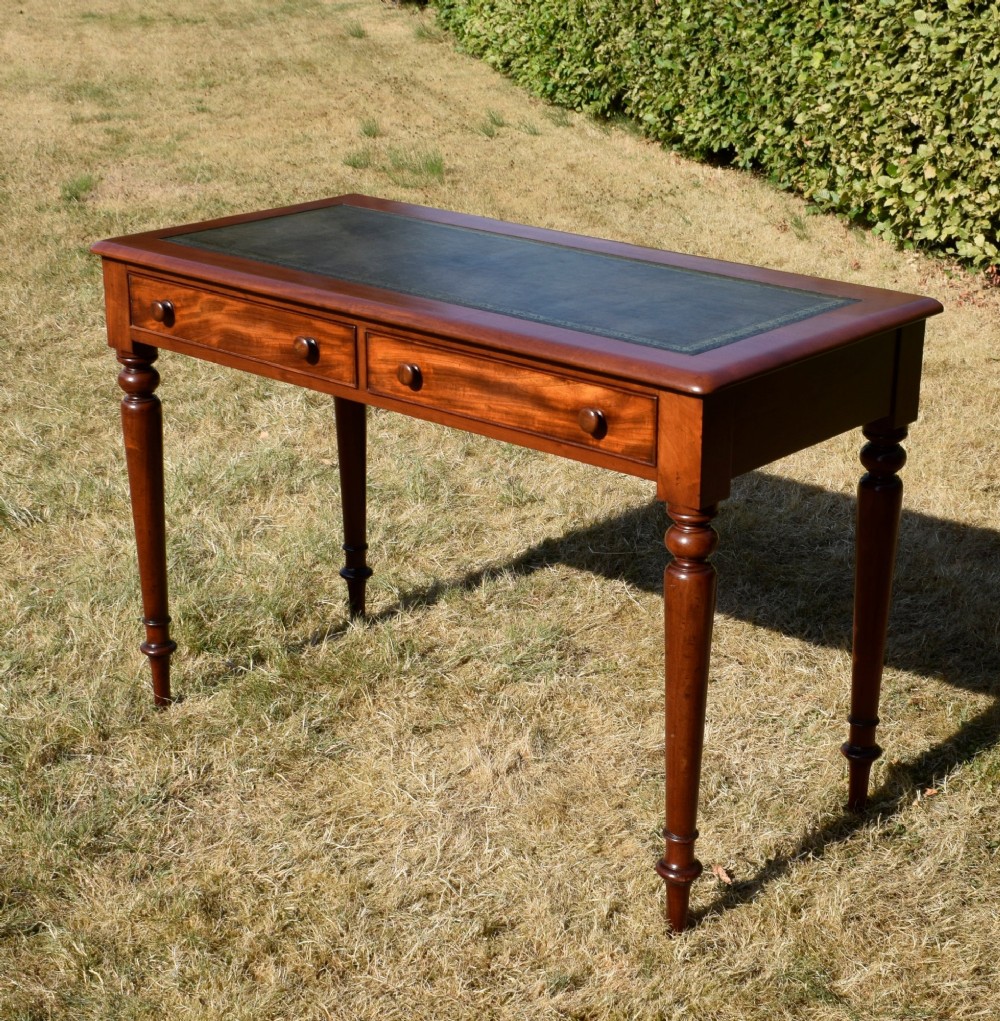 A Victorian mahogany writing desk featuring a green leather inset top with gold tooling, two frieze drawers with turned knob handles, and four slender turned legs. View II