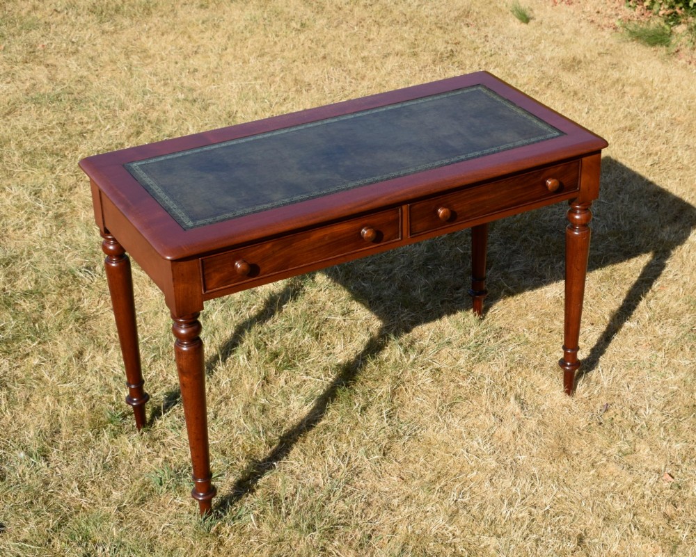 A Victorian mahogany writing desk featuring a green leather inset top with gold tooling, two frieze drawers with turned knob handles, and four slender turned legs. View IV