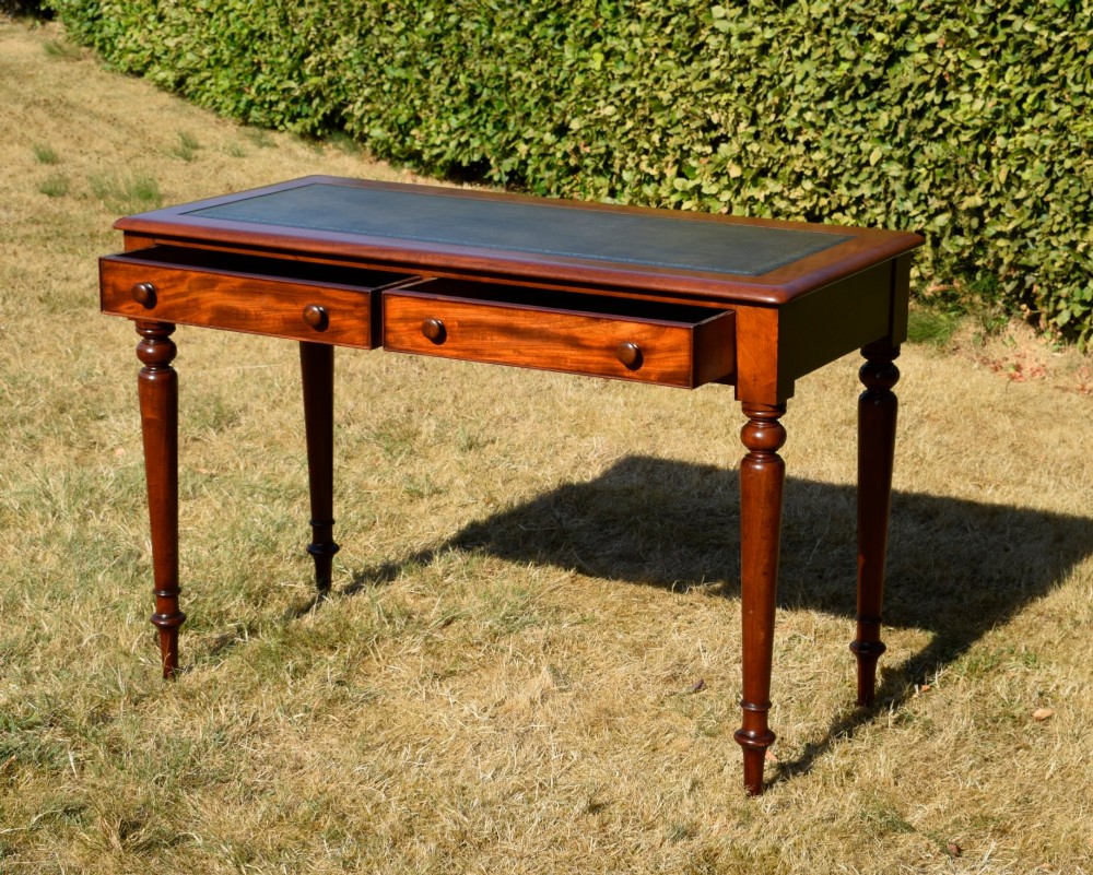 A Victorian mahogany writing desk featuring a green leather inset top with gold tooling, two frieze drawers with turned knob handles, and four slender turned legs. View IX