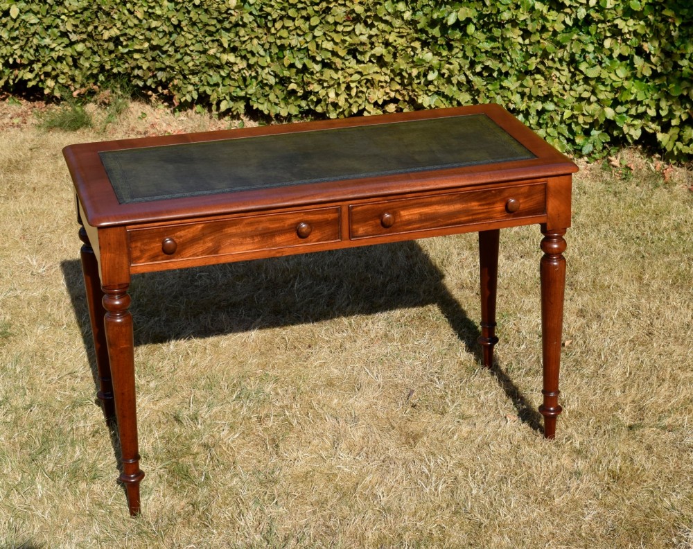 A Victorian mahogany writing desk featuring a green leather inset top with gold tooling, two frieze drawers with turned knob handles, and four slender turned legs. View XIV