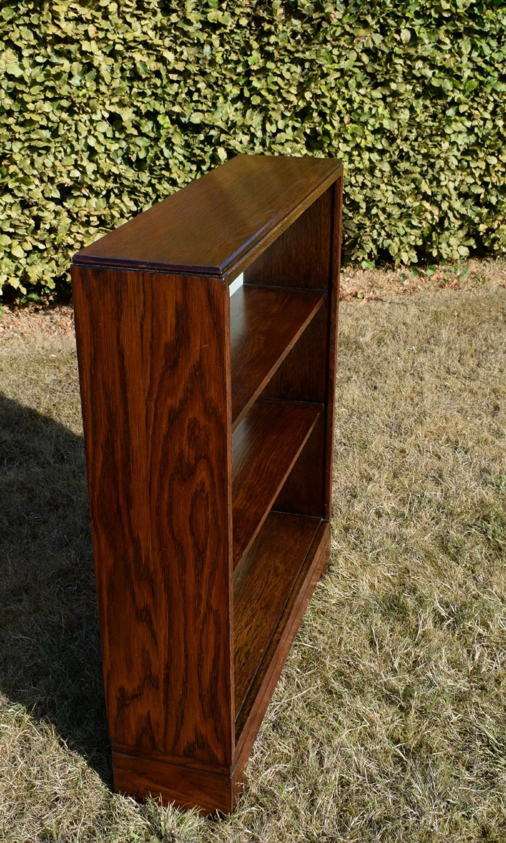 A dark oak Art Deco open bookcase featuring three shelves and a light duck-egg blue textured back panel. View VI