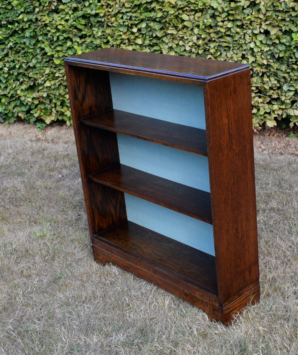 A dark oak Art Deco open bookcase featuring three shelves and a light duck-egg blue textured back panel. View VIII