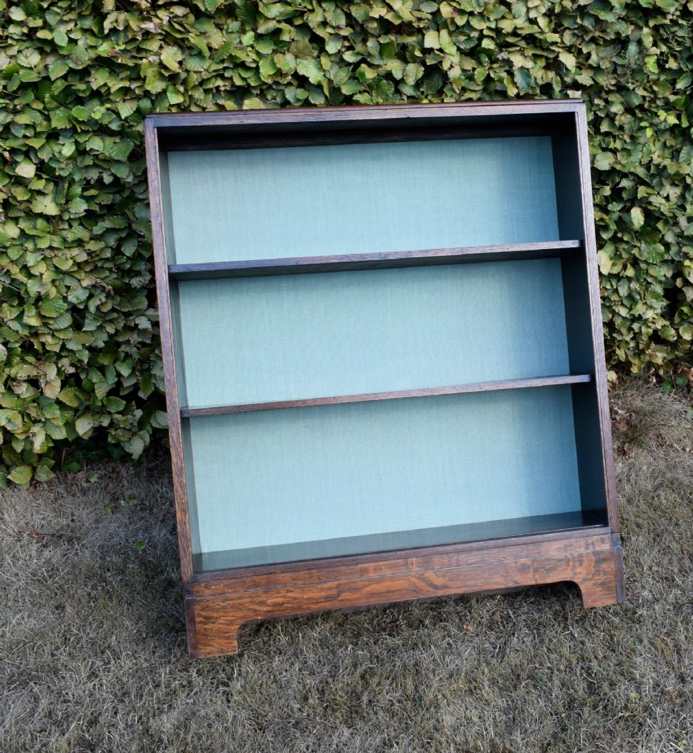 A dark oak Art Deco open bookcase featuring three shelves and a light duck-egg blue textured back panel. View X