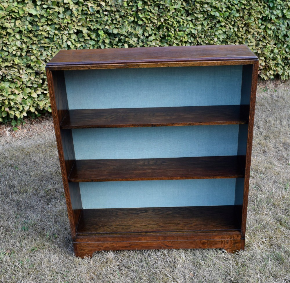A dark oak Art Deco open bookcase featuring three shelves and a light duck-egg blue textured back panel. View XI