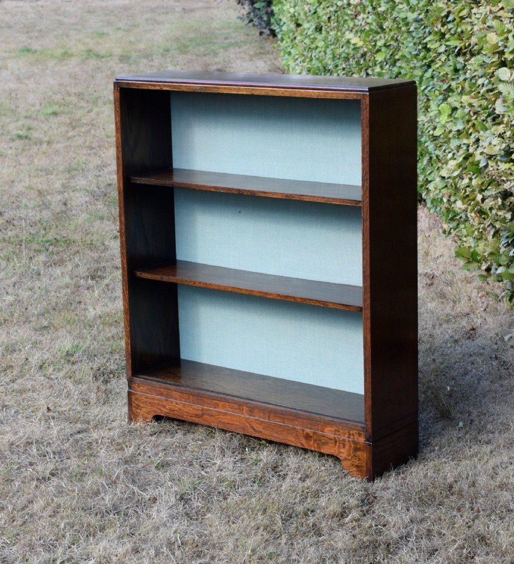 A dark oak Art Deco open bookcase featuring three shelves and a light duck-egg blue textured back panel. View XIV