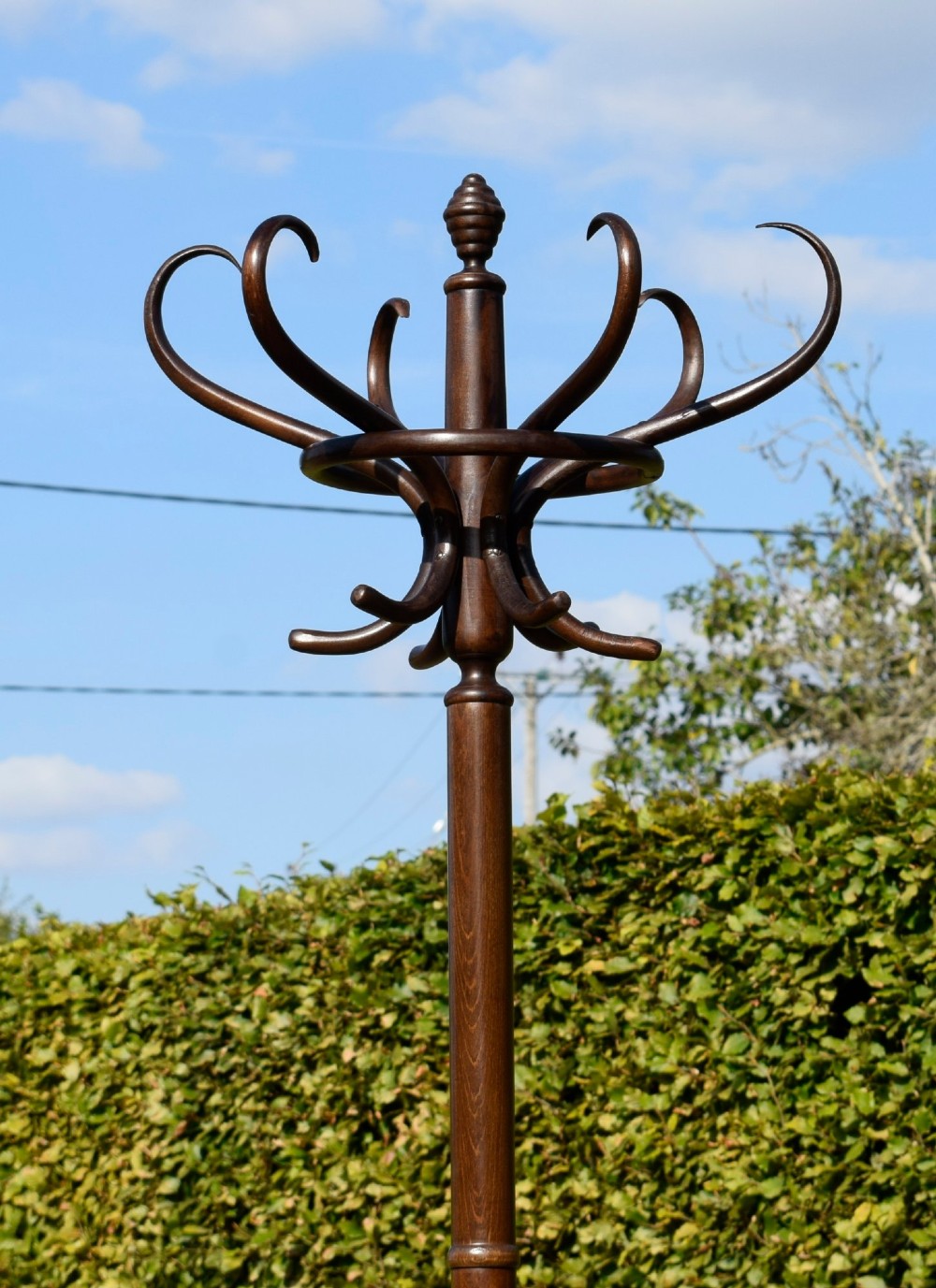 A dark brown bentwood coat and hat stand featuring curved upper hooks, a turned central post, an umbrella ring, and curved tripod legs. View III