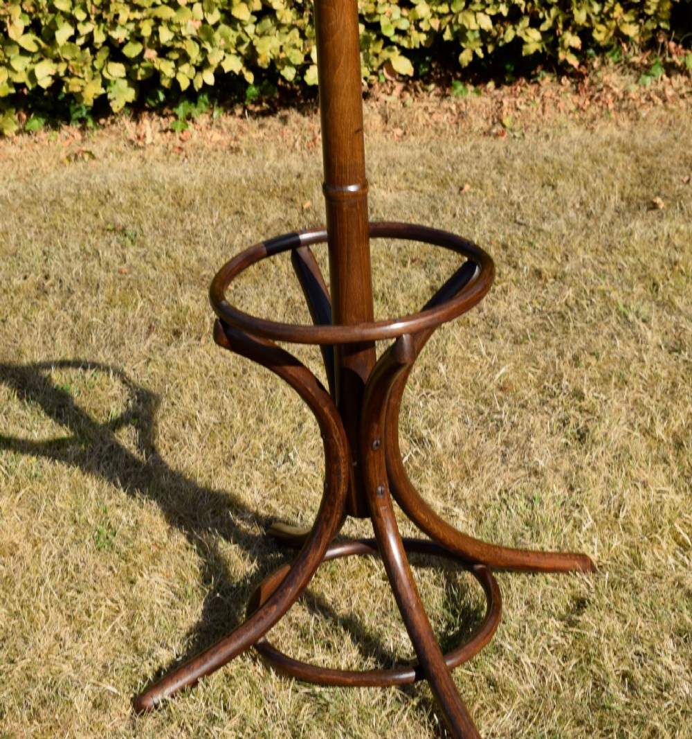 A dark brown bentwood coat and hat stand featuring curved upper hooks, a turned central post, an umbrella ring, and curved tripod legs. View VII