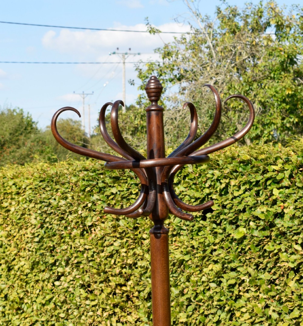 A dark brown bentwood coat and hat stand featuring curved upper hooks, a turned central post, an umbrella ring, and curved tripod legs. View IX