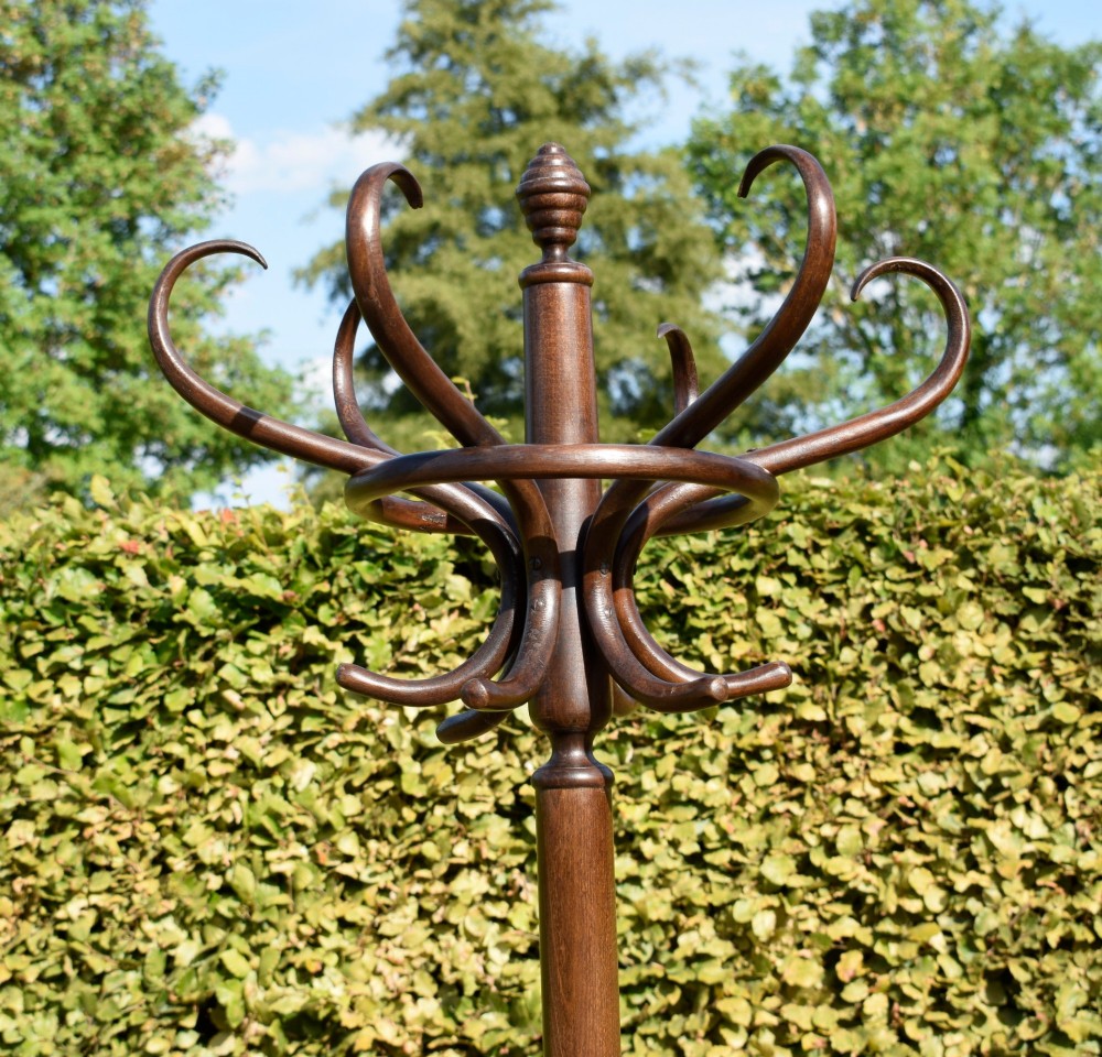 A dark brown bentwood coat and hat stand featuring curved upper hooks, a turned central post, an umbrella ring, and curved tripod legs. View X