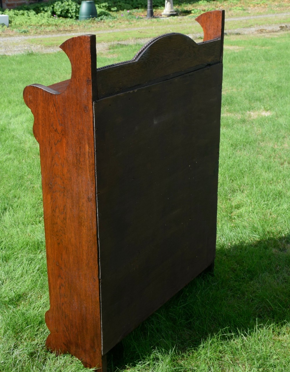An early twentieth-century open oak bookcase featuring a carved floral crest on the top gallery, shaped sides, and three fixed shelves. View VII