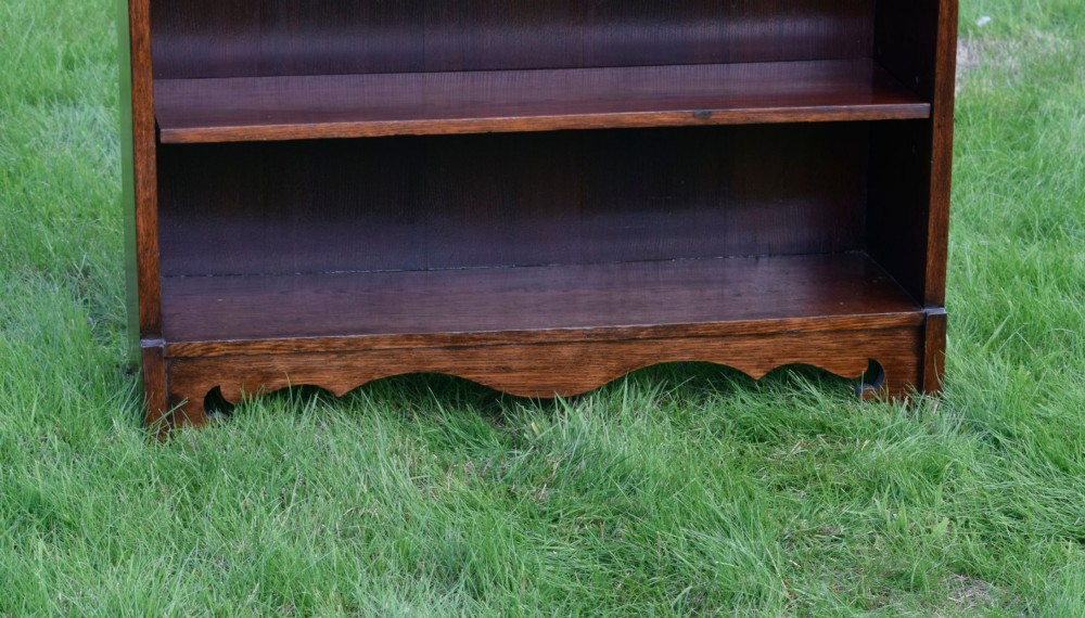 An early 20th-century open dark oak bookcase with four shelves, a low top gallery, and a scalloped plinth base. View III