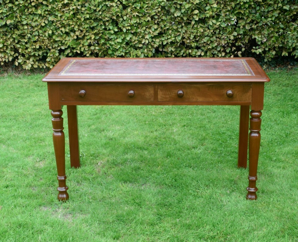 A Victorian mahogany writing table with a red leather inset surface, two drawers with wooden knob handles, turned front legs, and square back legs. View II