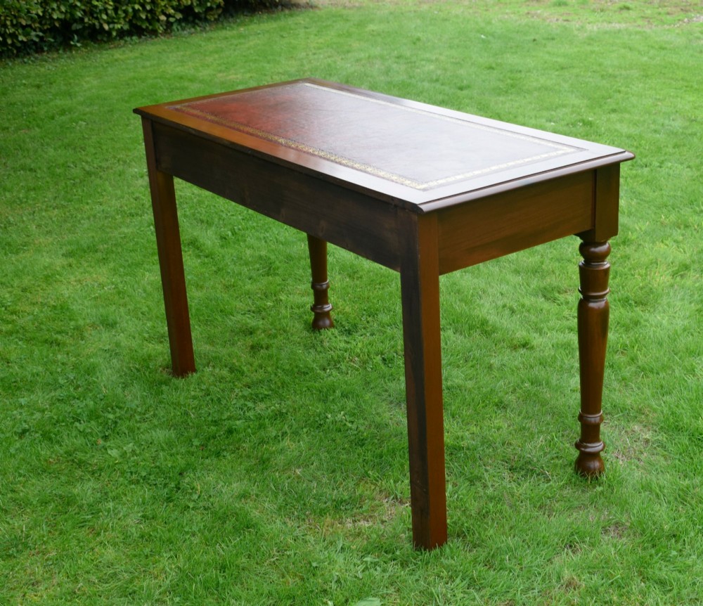 A Victorian mahogany writing table with a red leather inset surface, two drawers with wooden knob handles, turned front legs, and square back legs. View IV