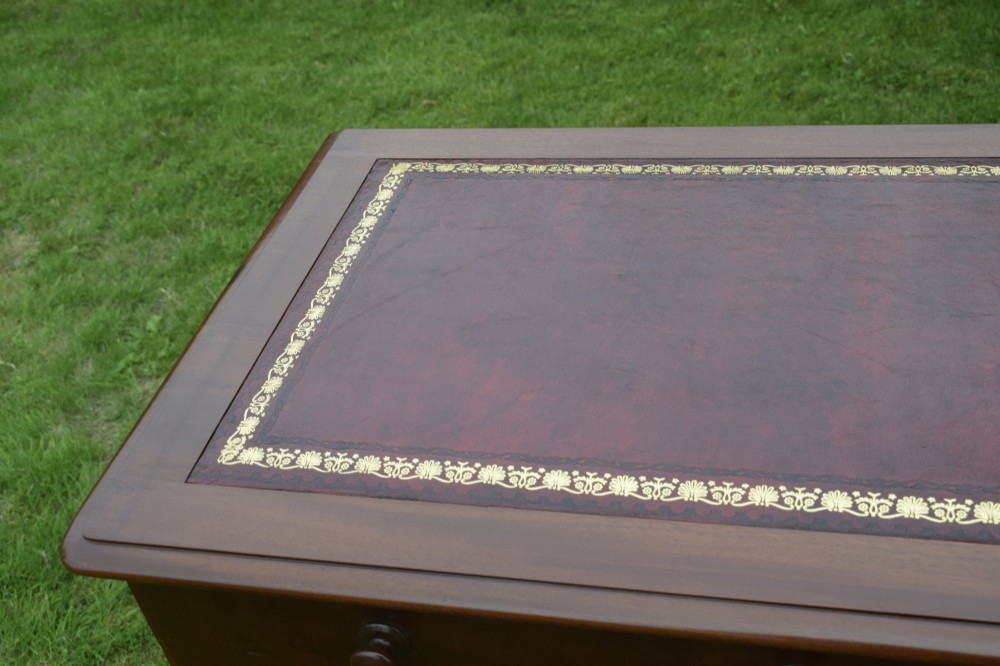 A Victorian mahogany writing table with a red leather inset surface, two drawers with wooden knob handles, turned front legs, and square back legs. View XI