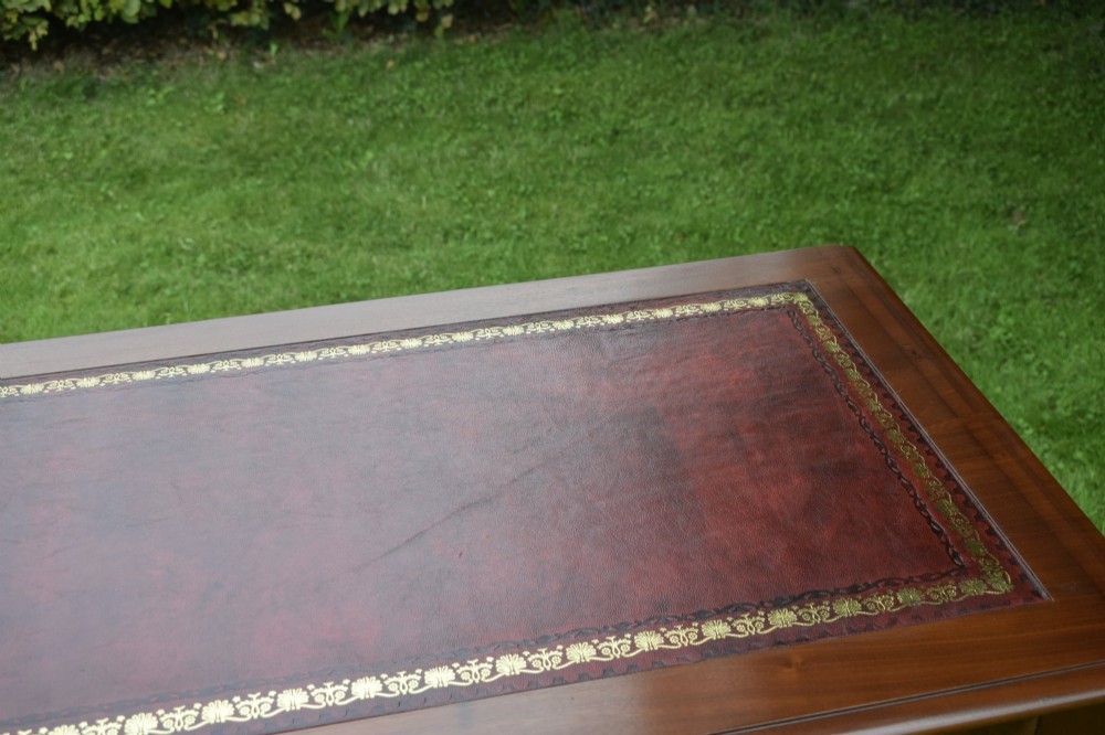 A Victorian mahogany writing table with a red leather inset surface, two drawers with wooden knob handles, turned front legs, and square back legs. View XII
