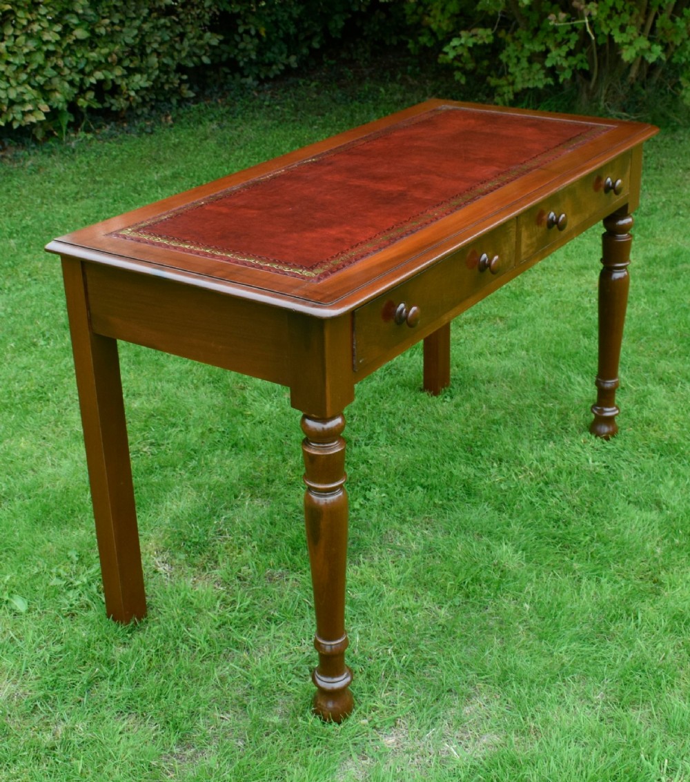 A Victorian mahogany writing table with a red leather inset surface, two drawers with wooden knob handles, turned front legs, and square back legs. View XIV