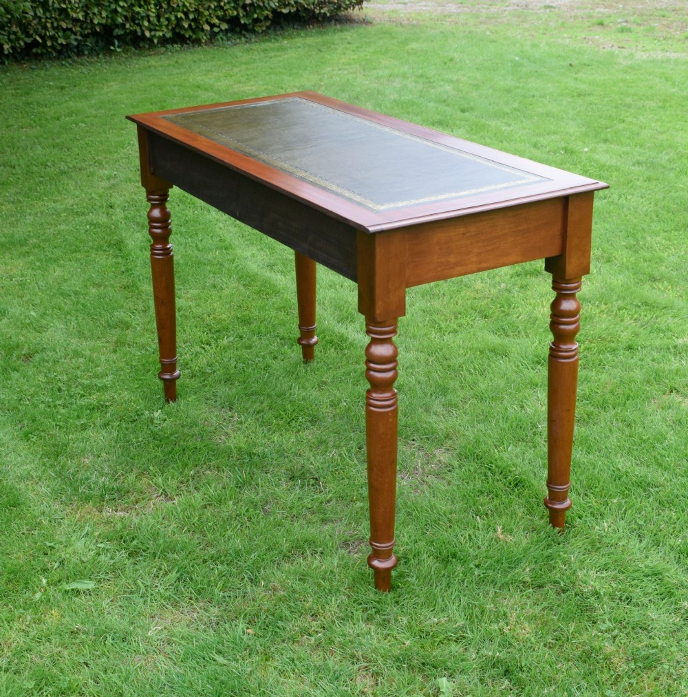 A Victorian warm brown mahogany writing table featuring an inset green leather writing surface, two drawers with knob handles, and turned legs. View XII