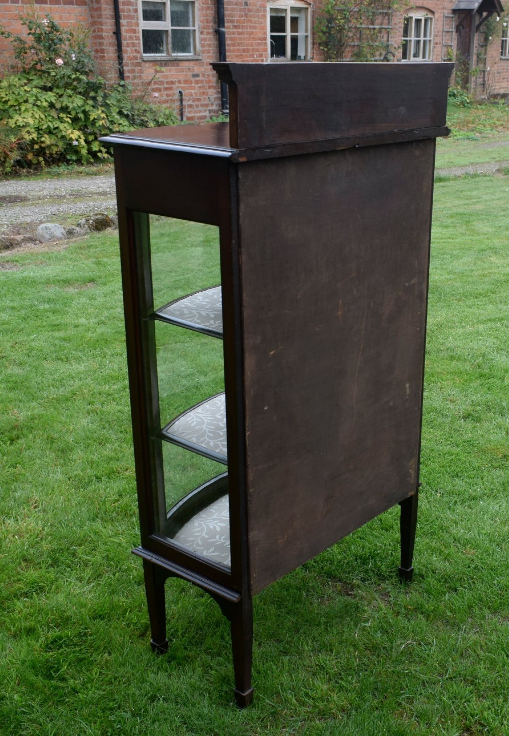 An Edwardian mahogany bowfront display cabinet featuring curved glass doors, satinwood string inlay, lined interior shelves, and tapered square legs. View X