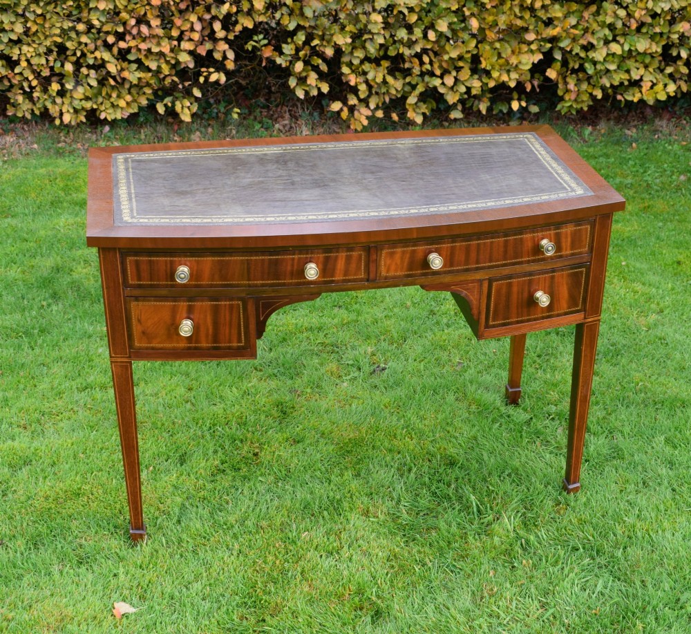 An Edwardian inlaid mahogany writing desk featuring a green leather inset top with gold tooling, four drawers with brass handles, and square tapered legs. View II