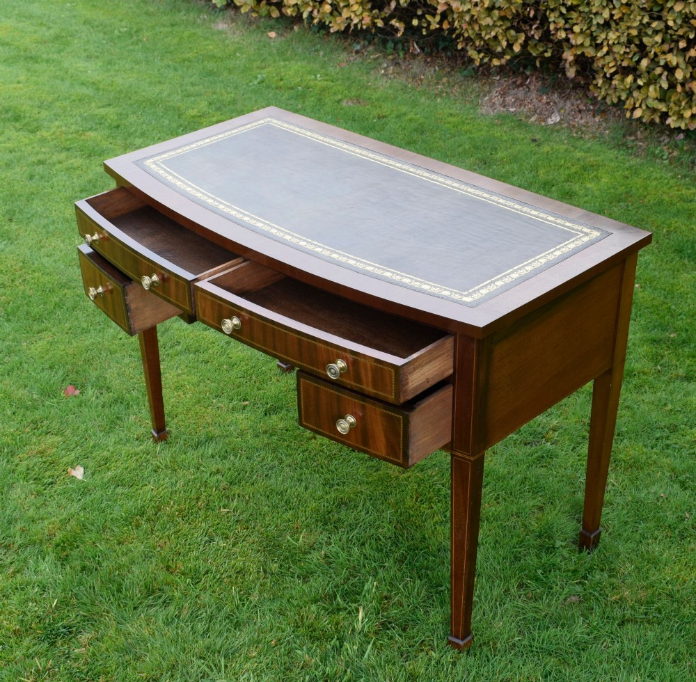 An Edwardian inlaid mahogany writing desk featuring a green leather inset top with gold tooling, four drawers with brass handles, and square tapered legs. View XIII