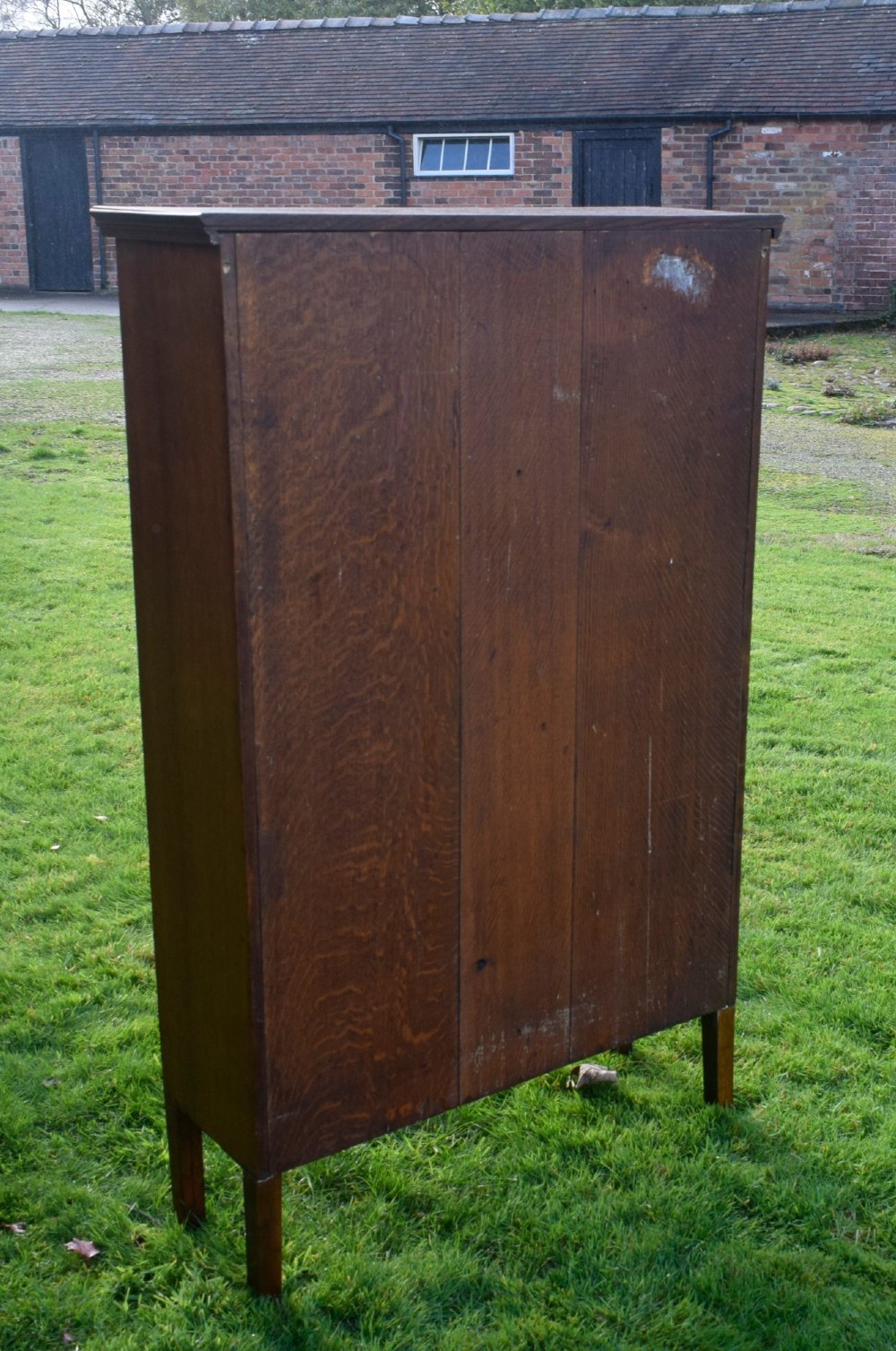 An early twentieth-century warm brown oak bookcase featuring twin glazed doors, brass hardware, and three internal shelves. View IV