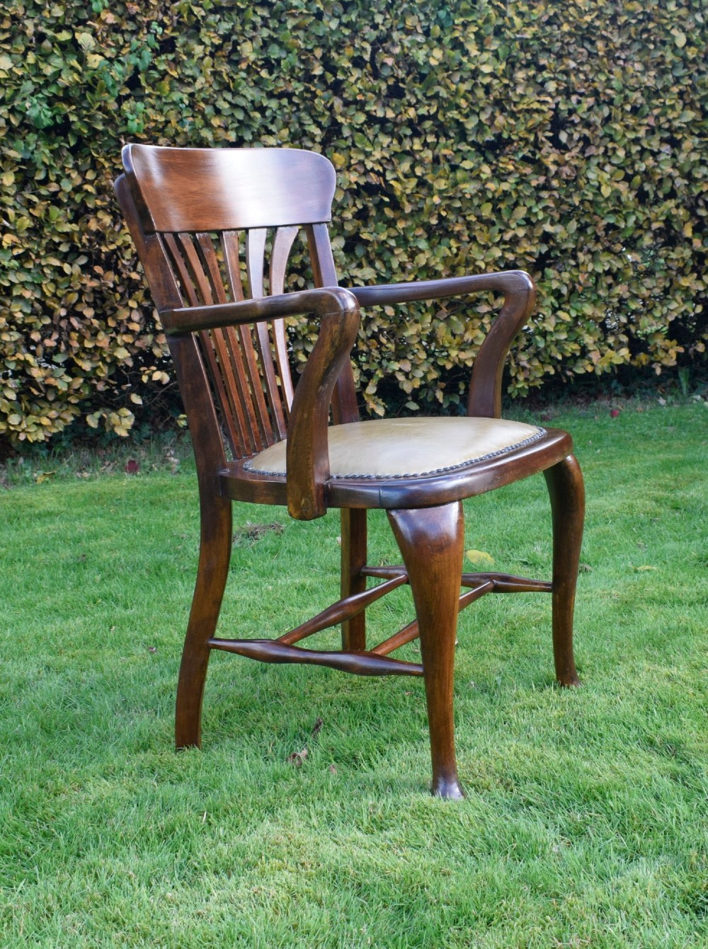 A late Victorian wooden desk armchair with a curved slatted backrest, curved arms, and a tan leather seat trimmed with studding. View IX