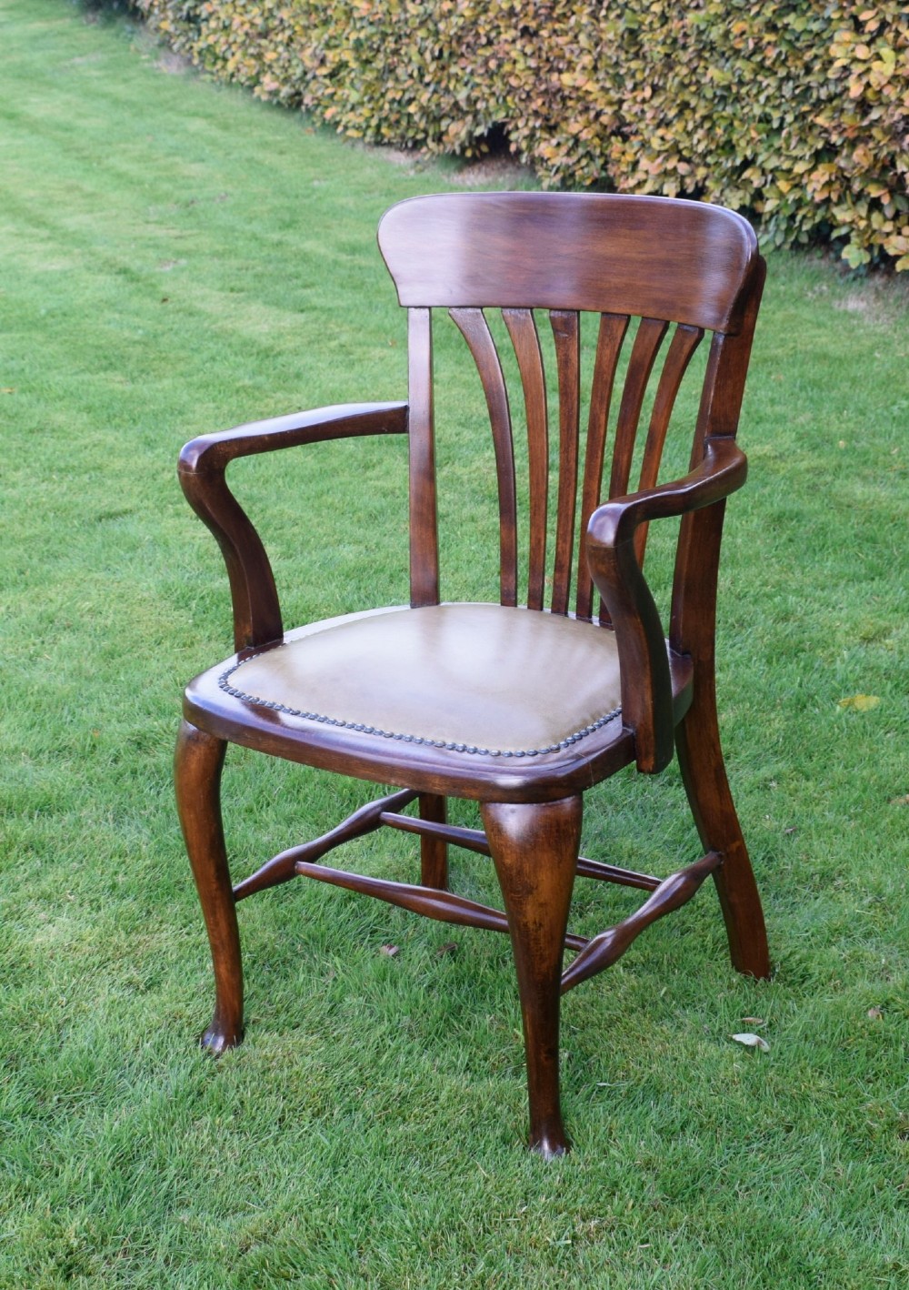 A late Victorian wooden desk armchair with a curved slatted backrest, curved arms, and a tan leather seat trimmed with studding. View XIII