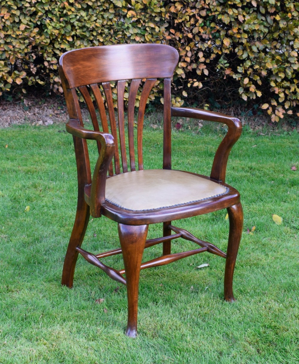 A late Victorian wooden desk armchair with a curved slatted backrest, curved arms, and a tan leather seat trimmed with studding. View XIV