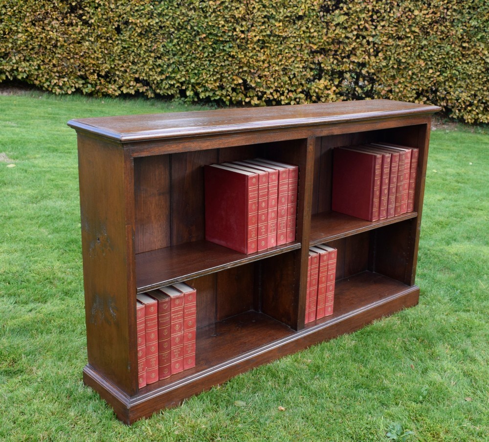 A wide early 20th-century low open oak bookcase with two main compartments, a central vertical divider, plank backboard, and a moulded top edge. View XIV