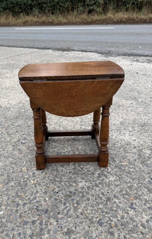 A small 1920s oak drop-leaf coffee table with turned legs and a warm brown finish.