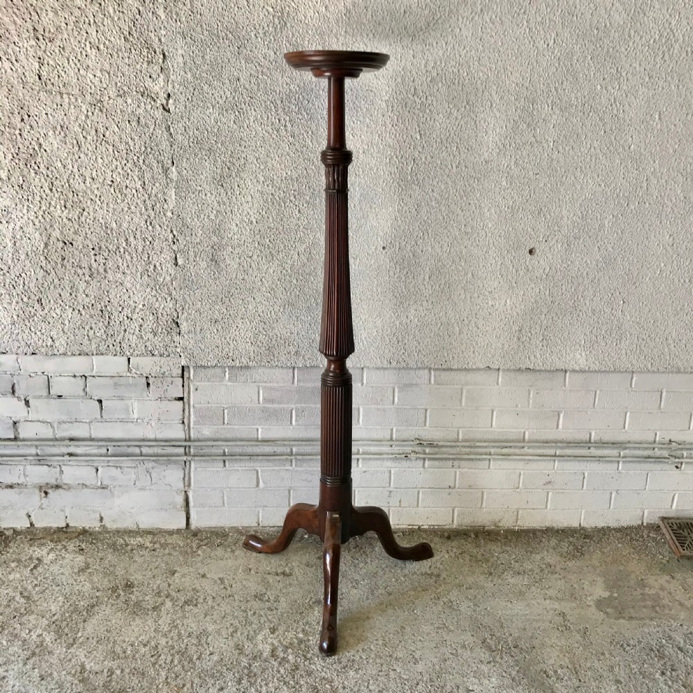 A tall Victorian dark mahogany torchere stand featuring a fluted central column, circular top, and carved tripod base.