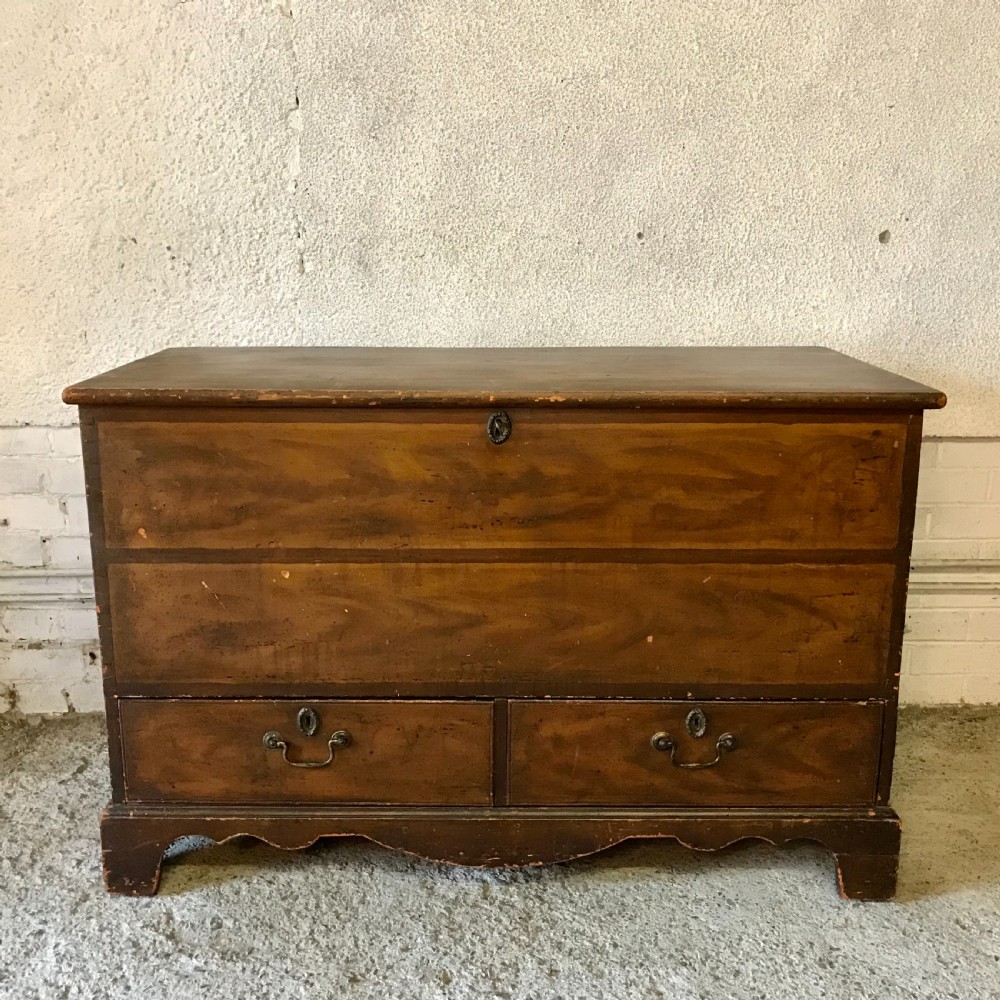 A 19th-century warm brown pine mule chest featuring a faux-grain painted finish, a hinged top compartment, and two lower drawers with metal handles.