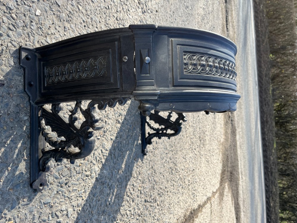 A pair of heavy black cast iron wall brackets featuring ornate dragon figures and geometric openwork patterning. View II