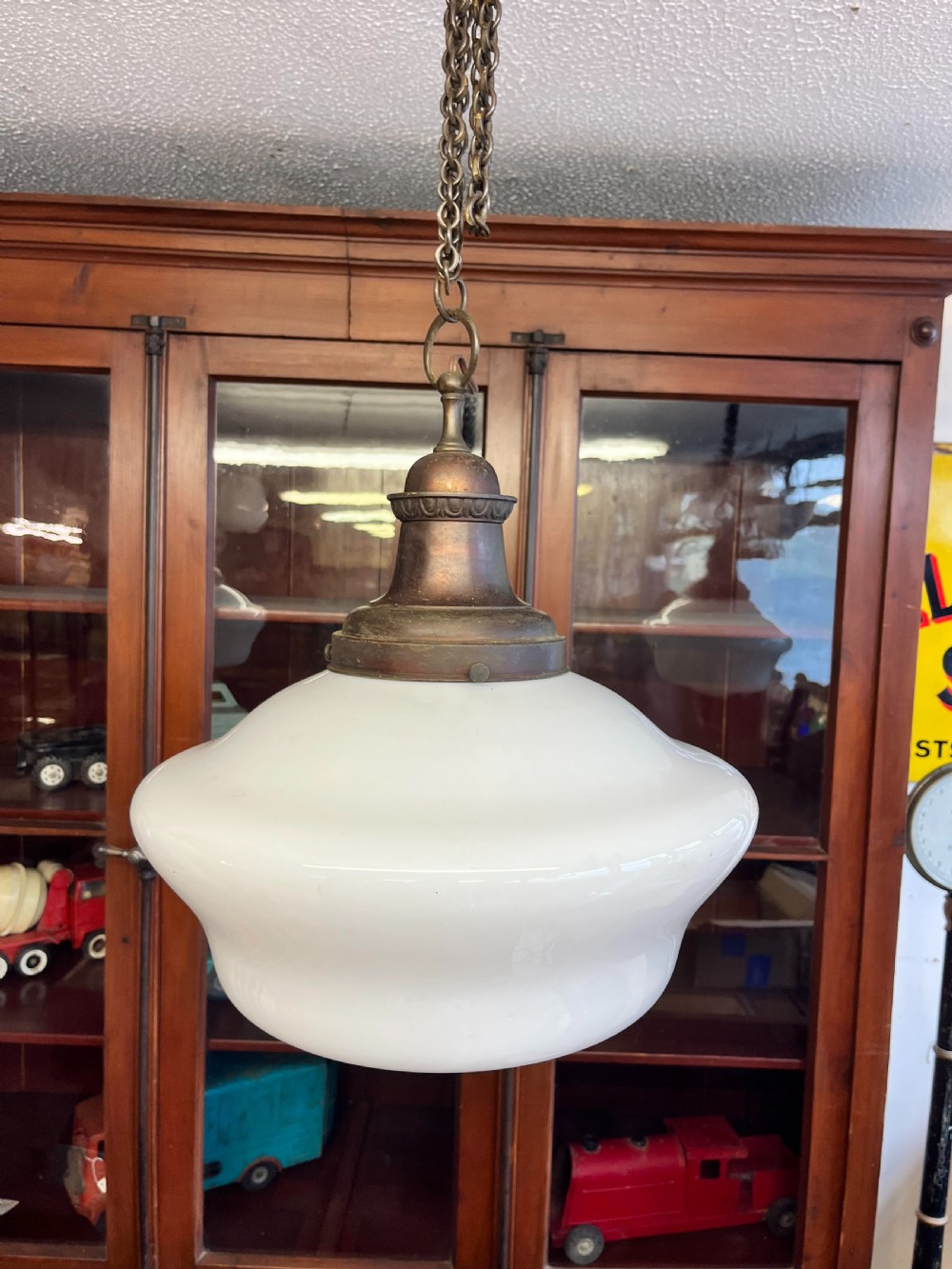 An early 20th-century white opaline glass chapel pendant light featuring a wide rounded shade, an aged brass gallery, and a suspension chain.
