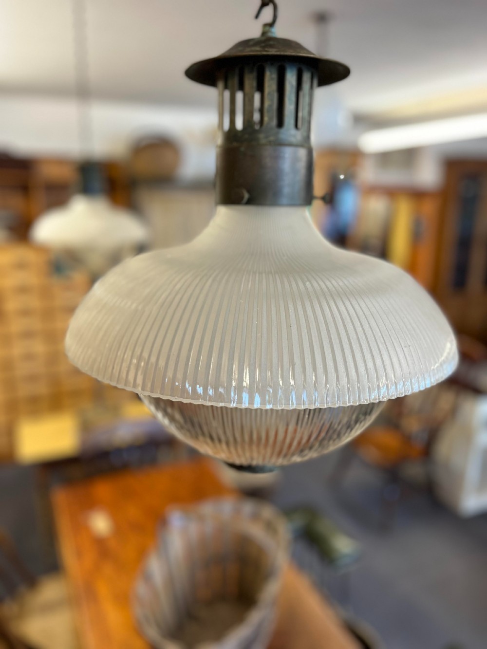An early twentieth-century double prismatic holophane glass pendant light with a slotted metal gallery and suspension hook.