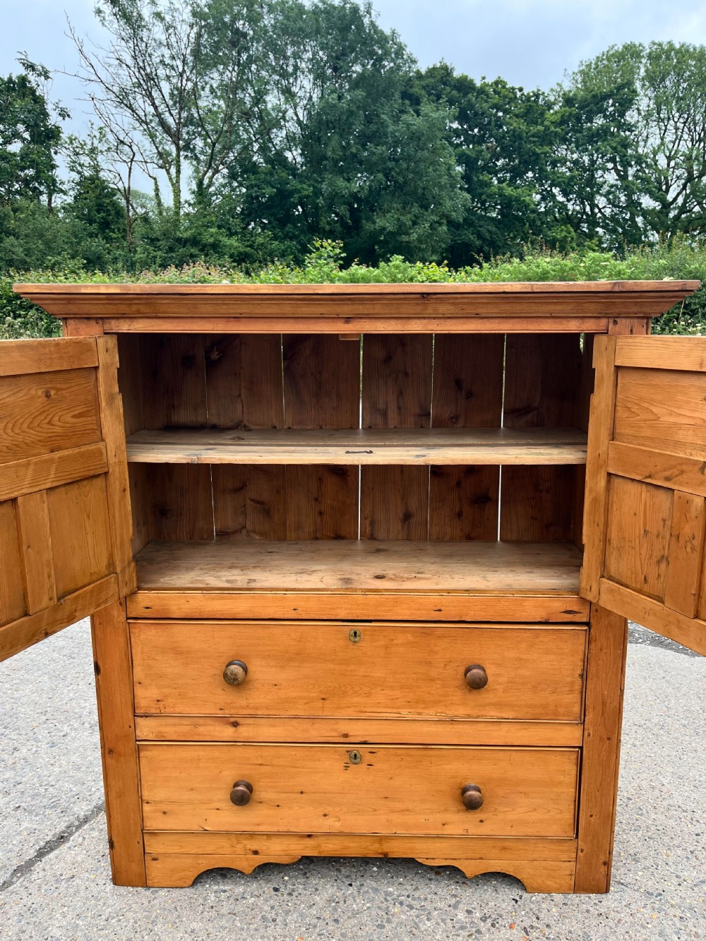 An early 19th-century Georgian pine linen cupboard featuring two upper panelled doors over two wide drawers with wooden turned knobs. View III