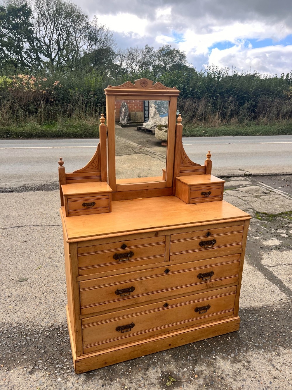 A Victorian pine dressing chest featuring a central swivel mirror flanked by two small trinket drawers, positioned above a base containing two short drawers and two long drawers with metal drop handles.