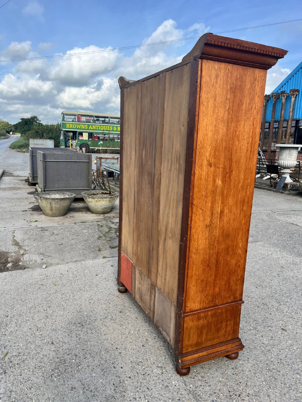 A turn-of-the-century Edwardian oak gentlemans wardrobe featuring a full-length mirrored door, relief-carved central panel, three carved front drawers, and iron strap hinges. View XII