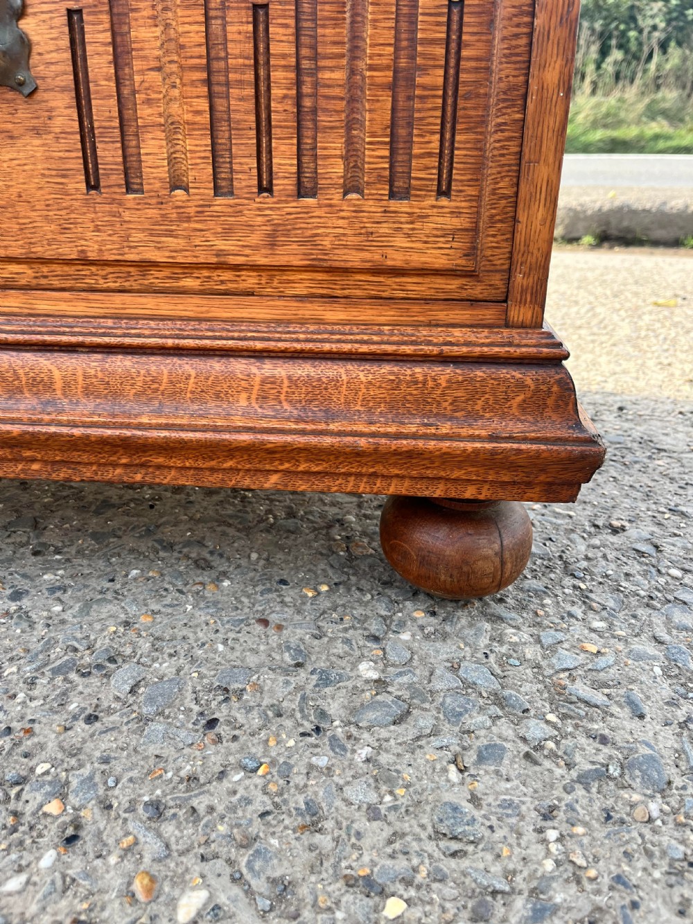 A turn-of-the-century Edwardian oak gentlemans wardrobe featuring a full-length mirrored door, relief-carved central panel, three carved front drawers, and iron strap hinges. View XIV