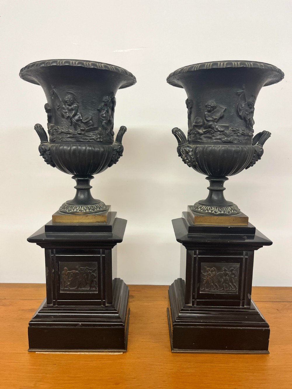 A Pair of Bronze Urns on Marble Plinths