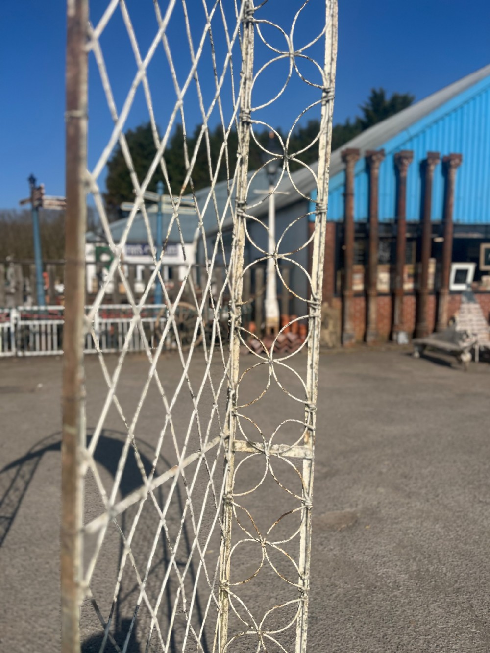 A tall early 20th-century wrought iron garden arch featuring interlocking circular side panels, a wirework canopy, and a weathered cream painted finish. View IX