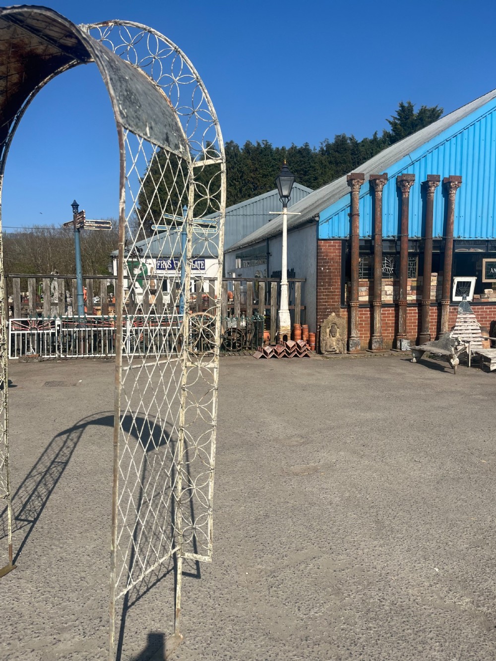 A tall early 20th-century wrought iron garden arch featuring interlocking circular side panels, a wirework canopy, and a weathered cream painted finish. View II