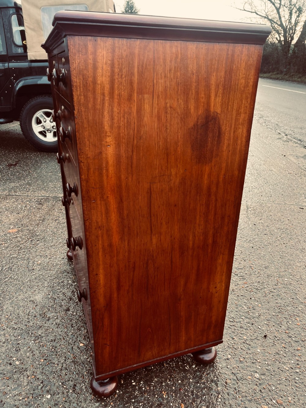 A late Georgian mahogany chest of drawers featuring two short drawers over four long graduated drawers with turned handles and brass keyhole escutcheons. View II