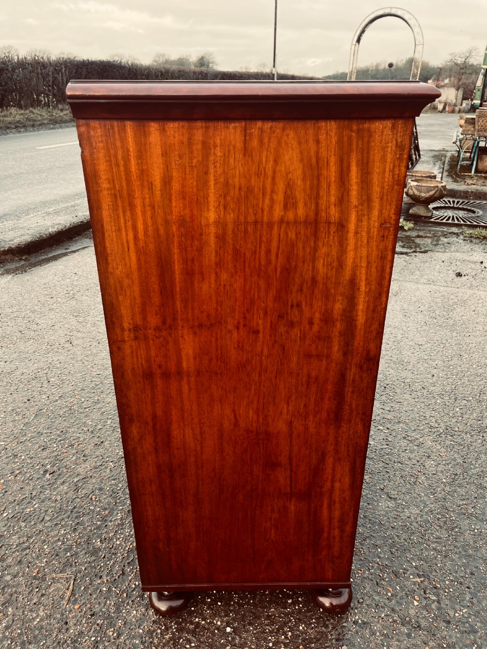 A late Georgian mahogany chest of drawers featuring two short drawers over four long graduated drawers with turned handles and brass keyhole escutcheons. View III