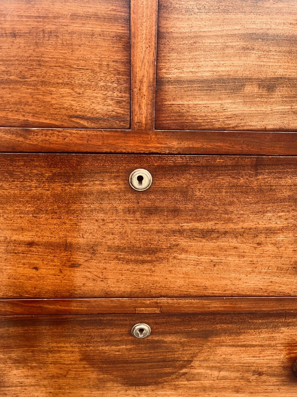 A late Georgian mahogany chest of drawers featuring two short drawers over four long graduated drawers with turned handles and brass keyhole escutcheons. View V