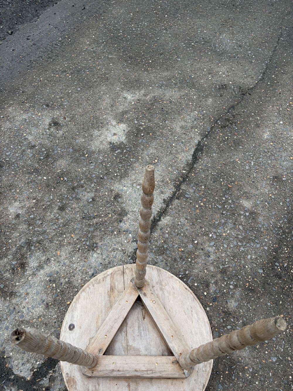 A nineteenth-century pine cricket table featuring a circular top supported by three bobbin-turned legs. View II