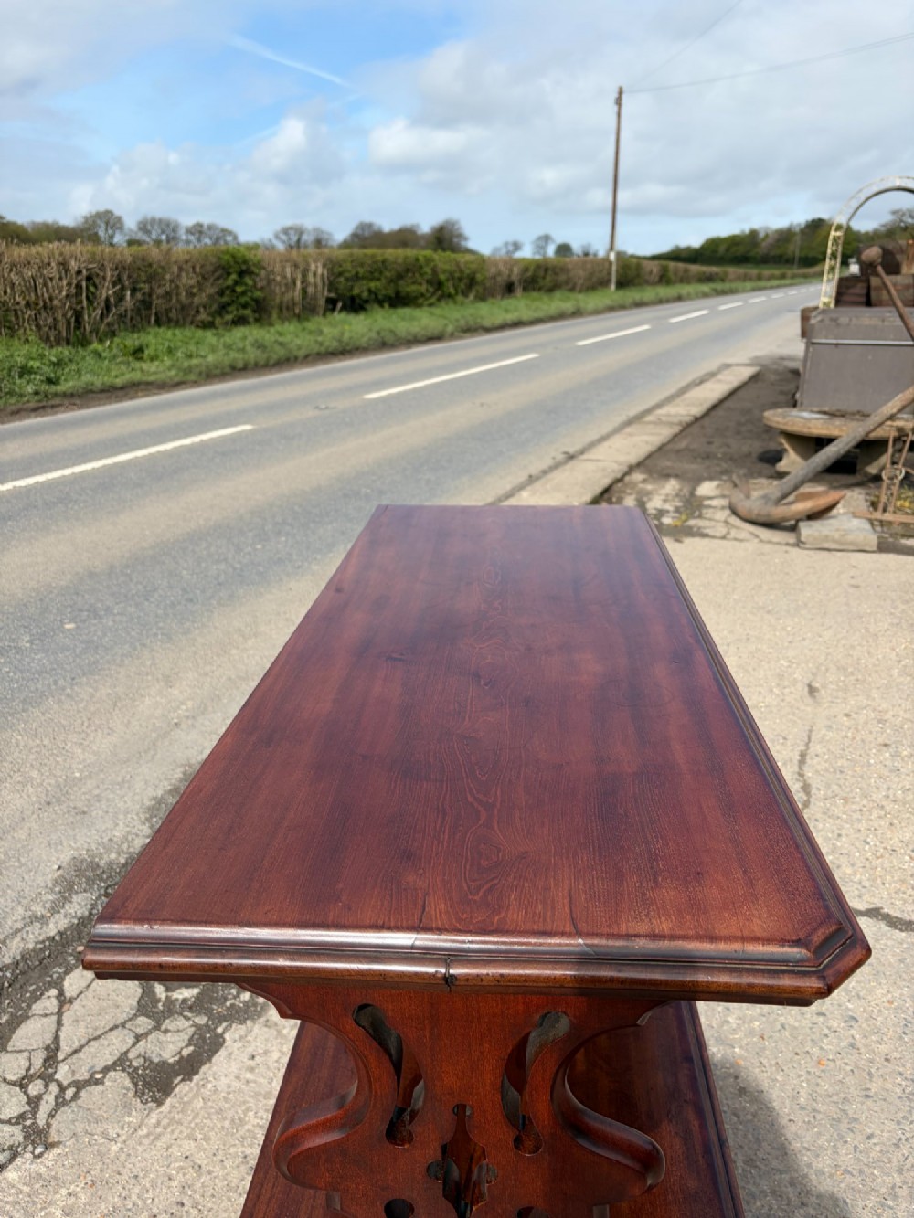 A Victorian mahogany three-tier buffet featuring carved pierced side supports, open rectangular shelves, and turned feet resting on original castors. View V