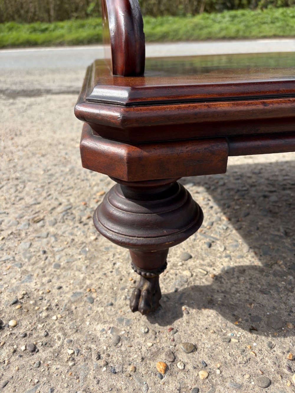 A Victorian mahogany three-tier buffet featuring carved pierced side supports, open rectangular shelves, and turned feet resting on original castors. View VI