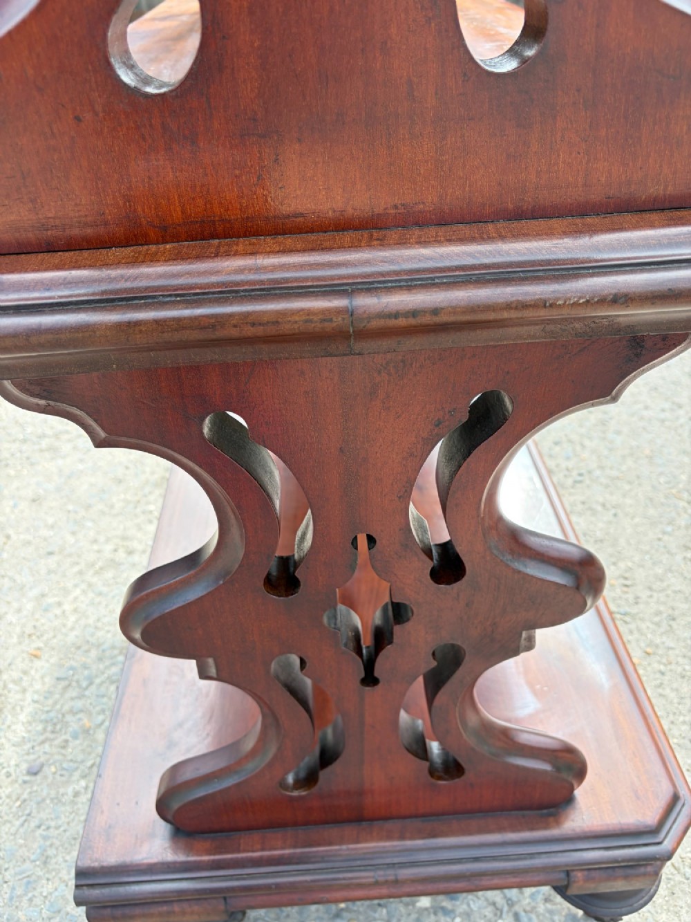 A Victorian mahogany three-tier buffet featuring carved pierced side supports, open rectangular shelves, and turned feet resting on original castors. View VII