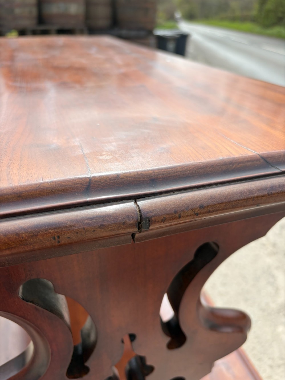 A Victorian mahogany three-tier buffet featuring carved pierced side supports, open rectangular shelves, and turned feet resting on original castors. View VIII
